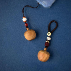 Flat-lay of two apple keepsake urn keychains on a blue background, showing the two strap styles.