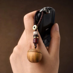 Hand holding a car key with a wooden apple keepsake urn keychain attached—small and easy to carry.