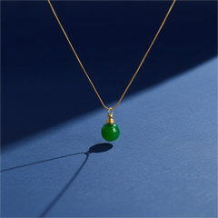 Natural green agate memorial pendant on gold chain, softly lit against blue background, minimal and elegant design."