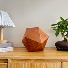 Lyra Pet Urn in sapele wood, icosahedron on tabletop, close-up grain detail.