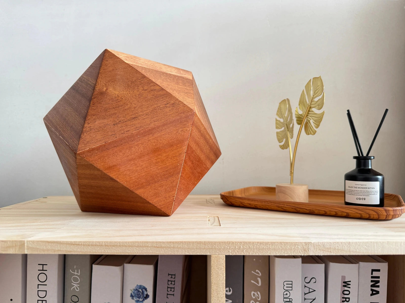 Lyra pet urn, Sapele icosahedron, on a bookcase in a bright home environment.