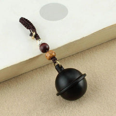 Black wooden ashes keychain on book — beaded strap detail