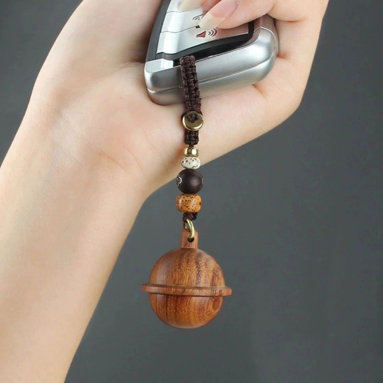 Wooden planet urn keychain held with car fob — handheld size