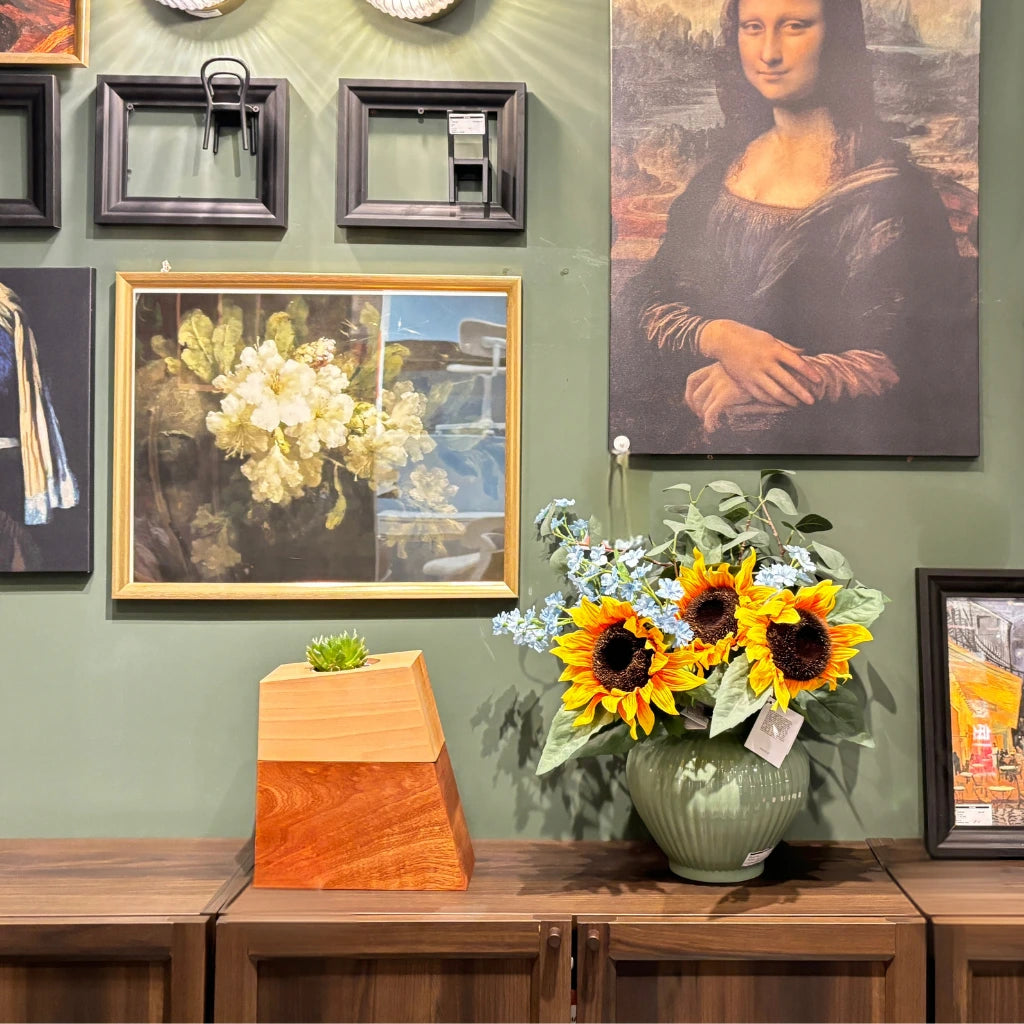 wood vase-style pet urn displayed on a shelf with sunflowers and framed art