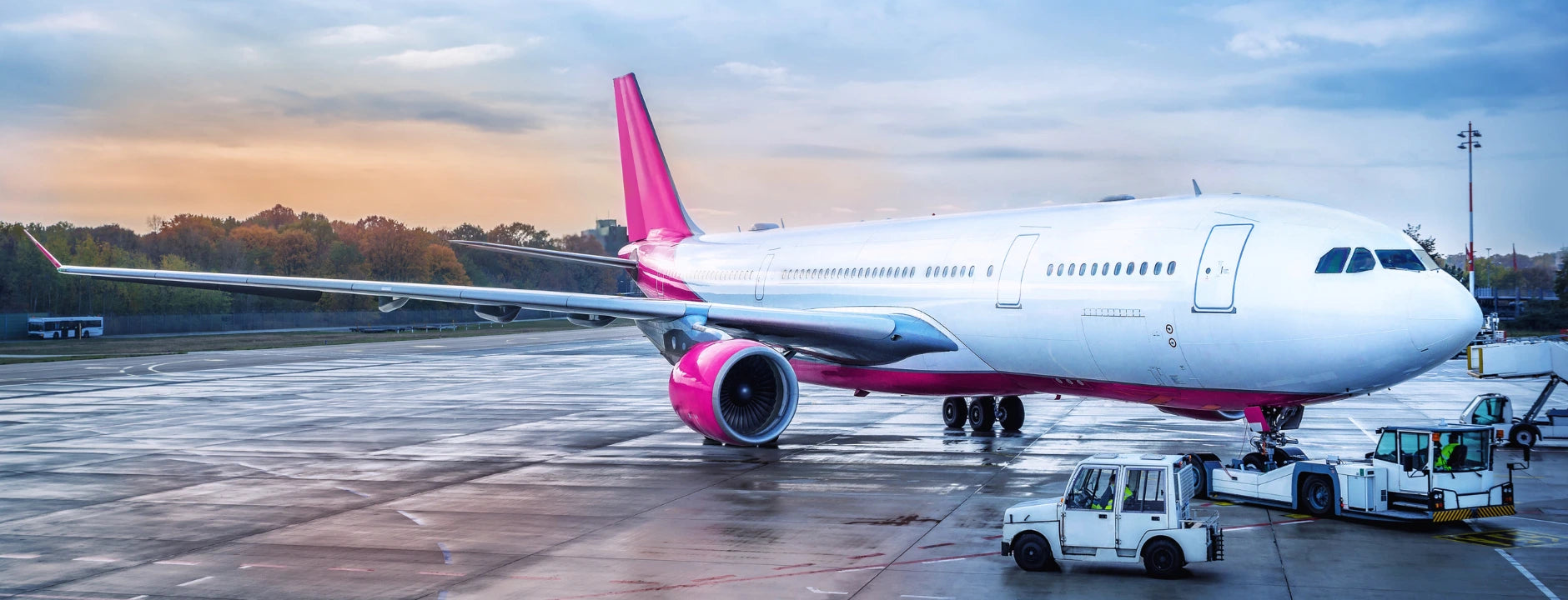  Wide banner of an aircraft on the tarmac with service vehicles — global shipping & easy returns.