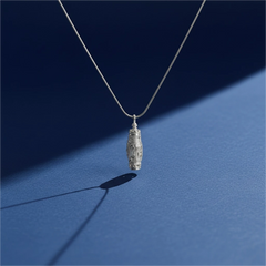 Snow Ridge micro-engraved ashes necklace — sterling-silver urn pendant on blue backdrop with soft side light and shadow.