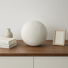 Bio Urn — biodegradable moon urn on wooden sideboard, crater texture
